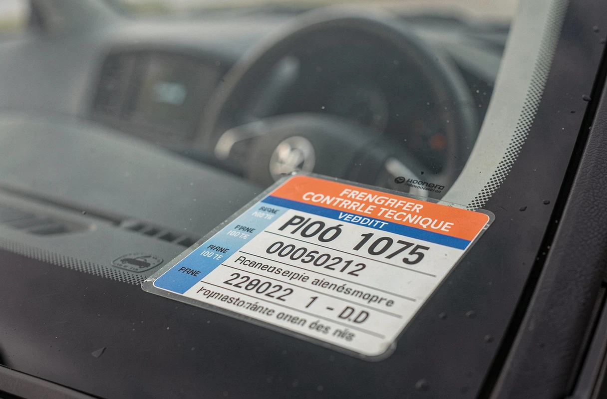 Vignette de contrôle technique française apposée sur le pare-brise d'une voiture avec date de validité visible